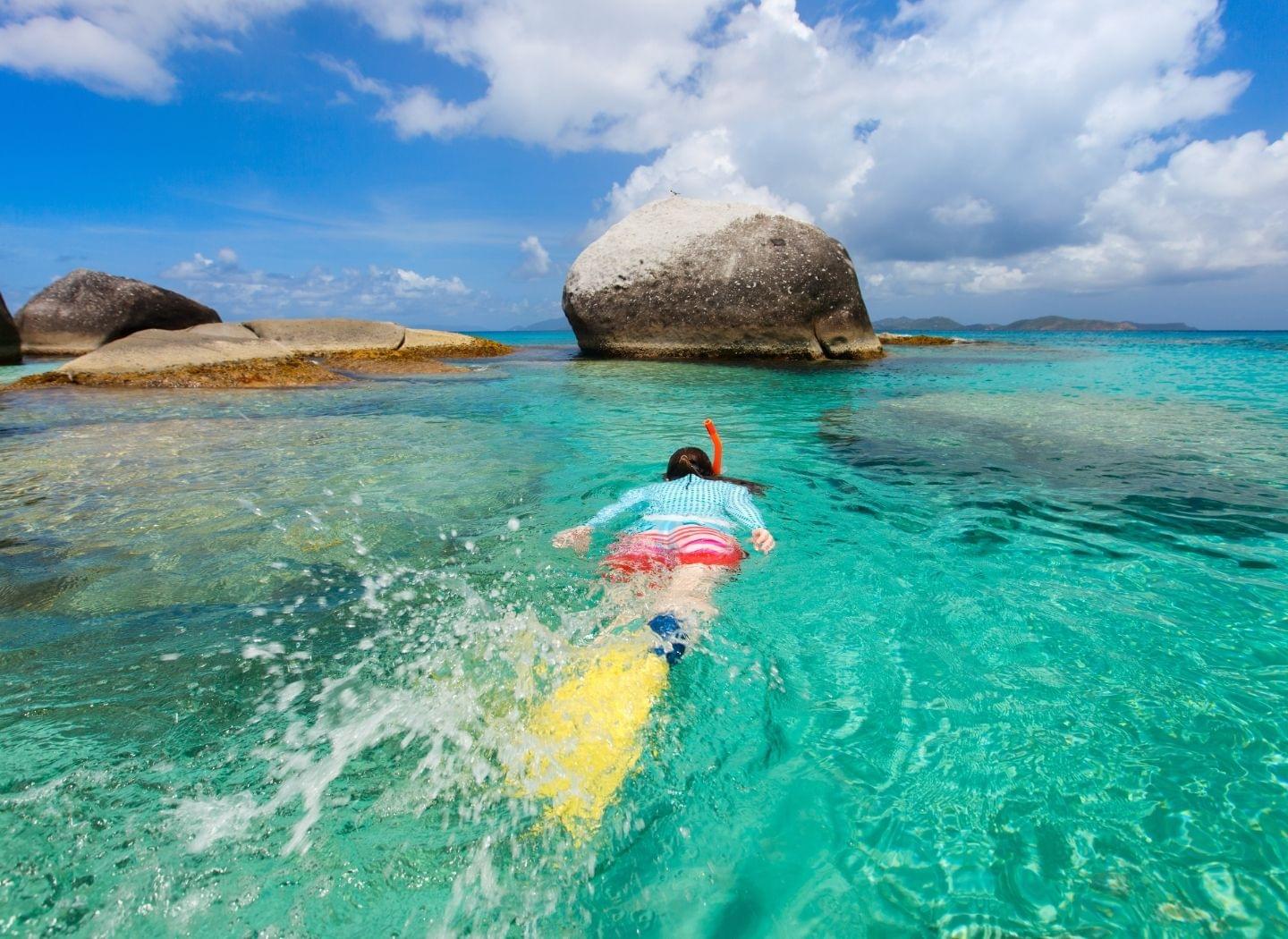 woman snorkeling around rocks