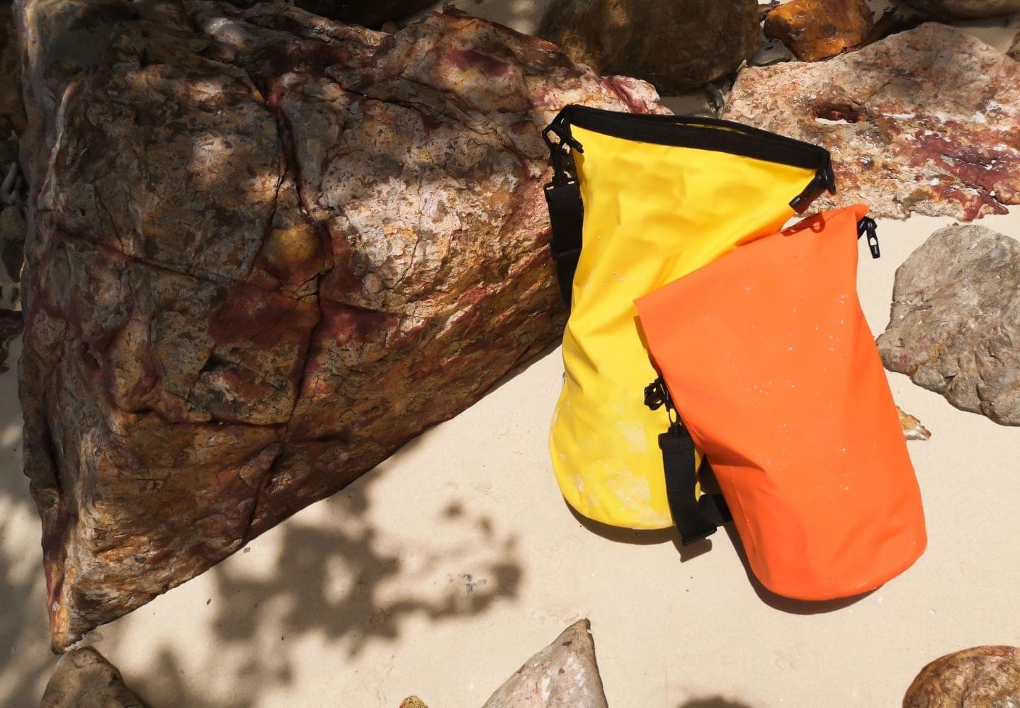 orange and yellow waterproof bag on beach